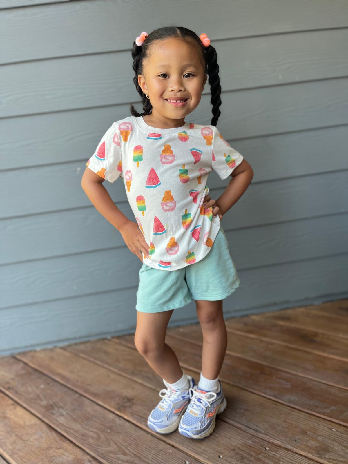 Milani in an ice cream print tee and mint shorts, hands on hips