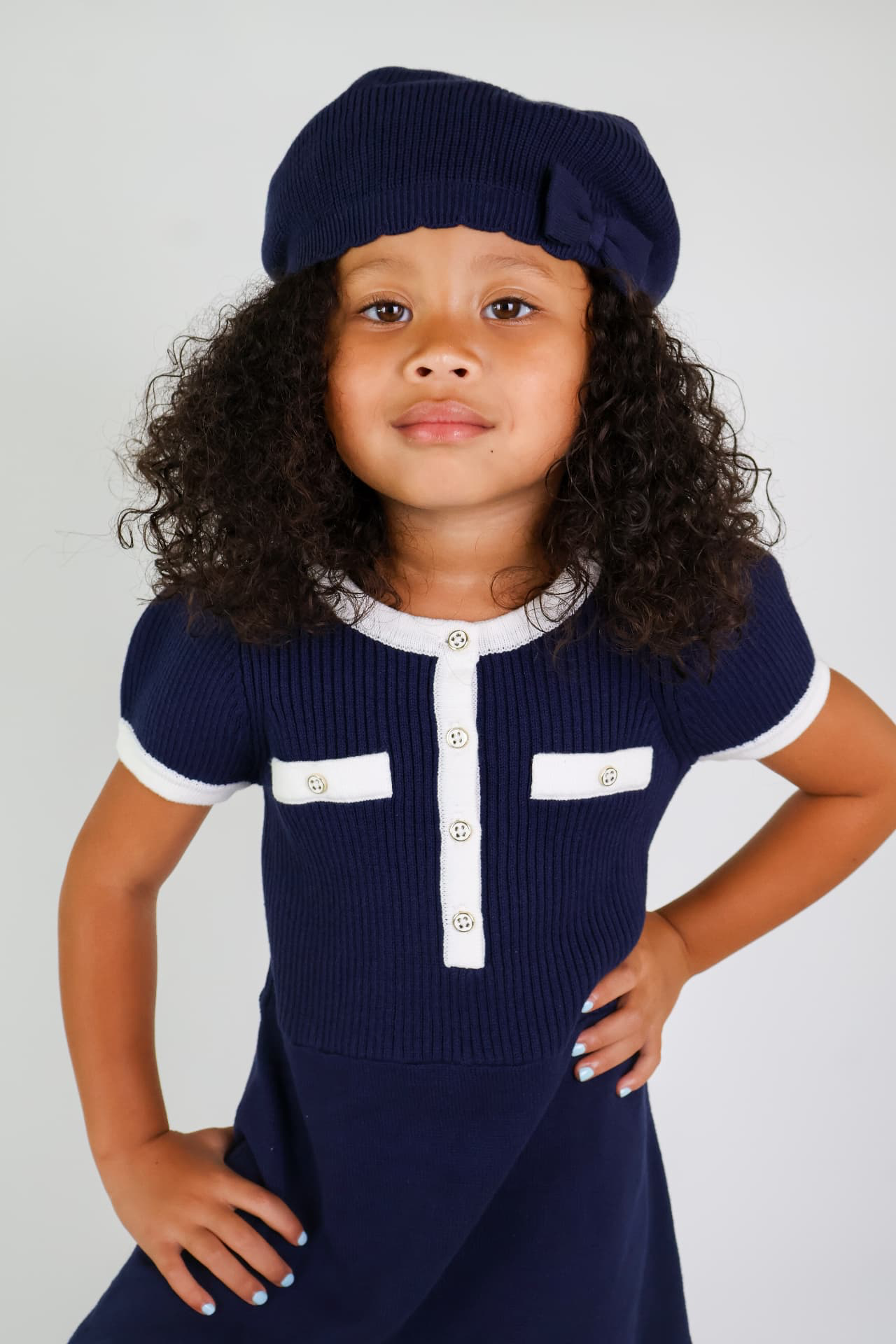 Milani posing in a navy knit dress and matching beret