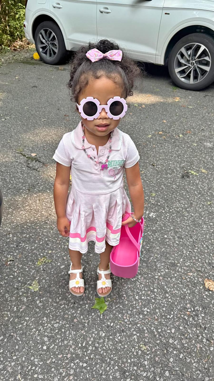 Milani in a pink polo dress with flower sunglasses and a pink tote