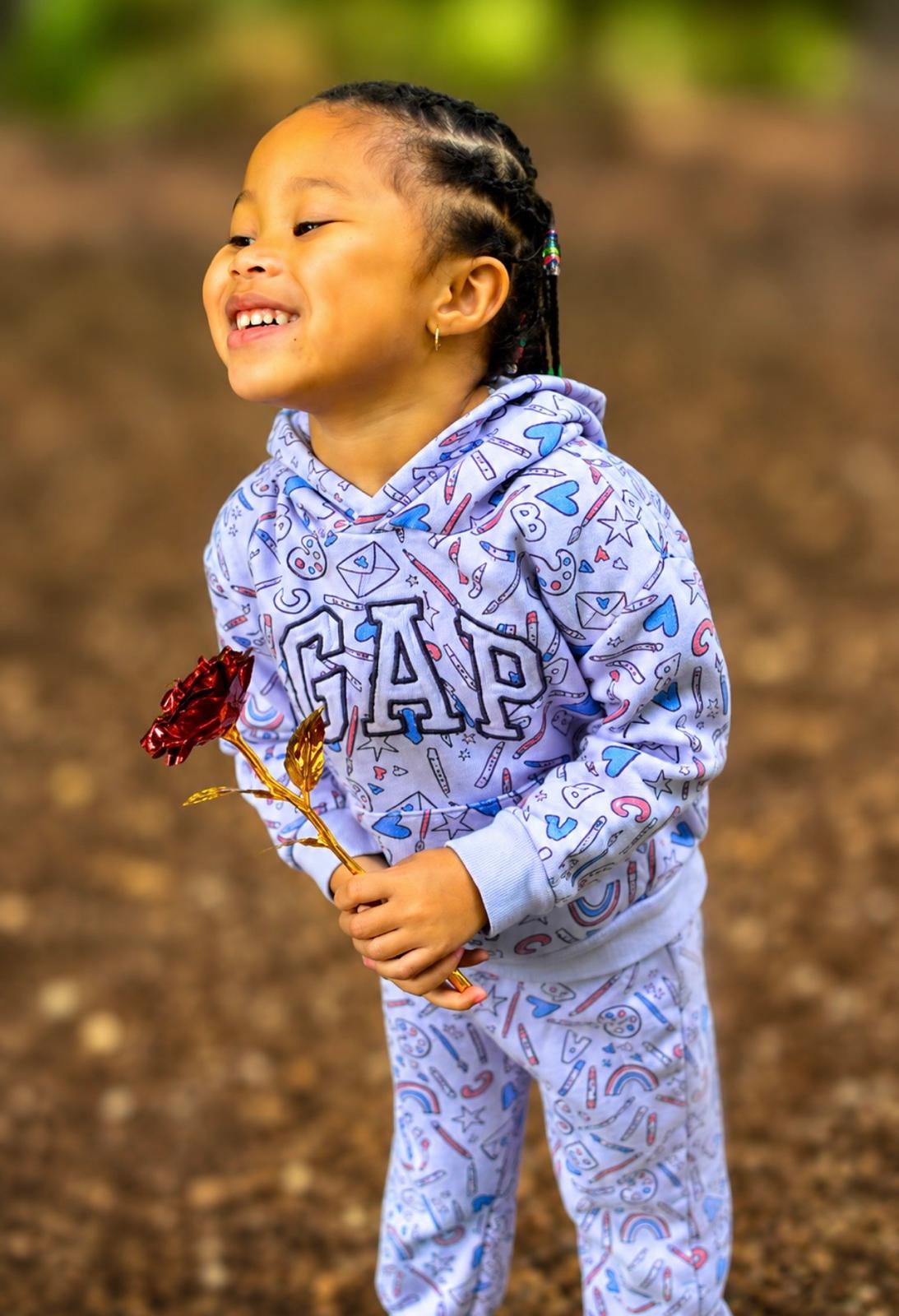 Milani laughing outdoors in a lavender printed hoodie and joggers
